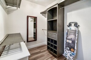 A compact room with a built-in ironing board, a mirror, and a wardrobe with shelves.