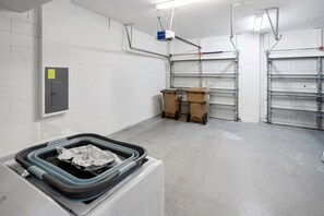A clean, empty industrial-style room with white brick walls, metal shelving units, and a large white machine in the foreground.