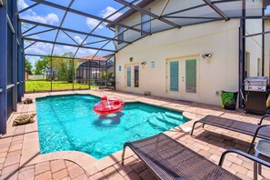 Una piscina exterior cubierta con sillas de descanso, una parrilla y vistas despejadas del entorno.