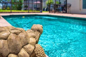 A stone turtle statue by a pool with a clear view of the pool's edge and a patio area in the background. - 4BR Villa|Pool•Game Room•Free BBQ|Disney (Clermont)