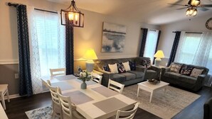 Una sala de estar moderna con comedor, que incluye un conjunto de sofá, una mesa de centro y una mesa de comedor con sillas.