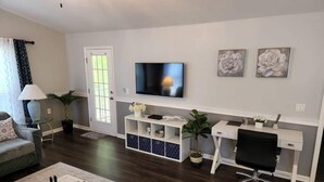Una sala de estar con sofá, mesa de centro, televisor y escritorio con silla.