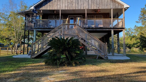 A wooden building with a balcony and a staircase leading to the entrance. - J & S's Pond Da Rosa  A Place Apart From The Rest (Bay St. Louis)