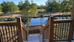 A wooden deck with a view of a pond and surrounding trees. - J & S's Pond Da Rosa  A Place Apart From The Rest (Bay St. Louis)