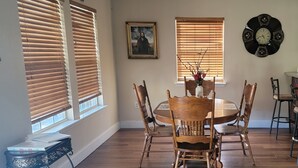 A dining area with a round wooden table, four chairs, and a vase with flowers on the table. - J & S's Pond Da Rosa  A Place Apart From The Rest (Bay St. Louis)