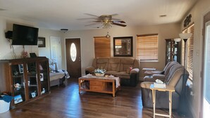 A living room with a wooden floor, two sofas, a coffee table, a ceiling fan, and a television. - J & S's Pond Da Rosa  A Place Apart From The Rest (Bay St. Louis)