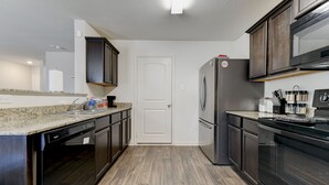 A modern kitchen with dark cabinetry, a stainless steel refrigerator, and a built-in oven. - Jarrell Jewel 💎 (Jarrell)
