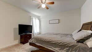A bedroom with a bed, a television on a stand, a ceiling fan, and a framed quote on the wall. - Jarrell Jewel 💎 (Jarrell)