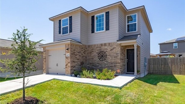 A two-story house with a garage, a brick facade, and a small tree in the front yard. - Jarrell Jewel 💎 (Jarrell)