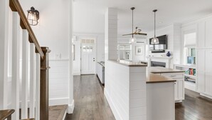 Una cocina moderna con armarios blancos, una isla de madera y un ventilador de techo.