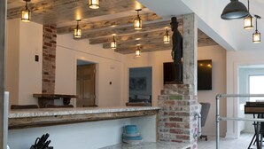 Una cocina con encimeras de granito, pared de ladrillo decorativa, lámparas colgantes y una estatua.