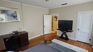 A living room with a flat-screen TV, wooden furniture, and a framed picture on the wall.