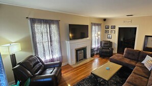 A living room with a fireplace, leather sofas, a flat-screen TV, and a coffee table.