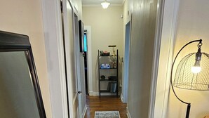 A hallway with wooden flooring, a rug, a ceiling light, and a floor lamp.