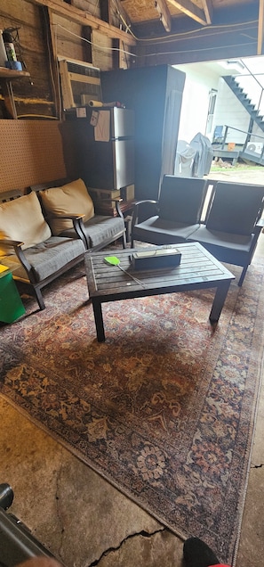 A room with a sofa, a coffee table, a patterned rug, and a staircase leading outside.