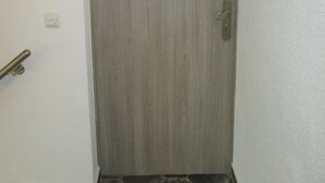 A closed door with a metallic handle and a small light switch on the wall to its left. - Vacation apartment in the heart of Saxony (Leisnig)