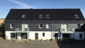 A two-story house with a dark roof, multiple windows, and a front porch with railings. - Vacation apartment in the heart of Saxony (Leisnig)