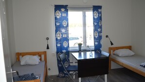 A small, well-lit room with a single bed, a desk with a chair, and a window with curtains. - Bollnäs vandrarhem (Bollnas)
