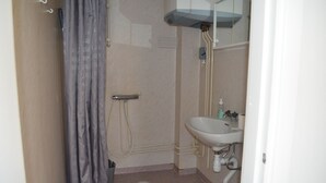 Een kleine badkamer met een douche, wastafel en toilet.