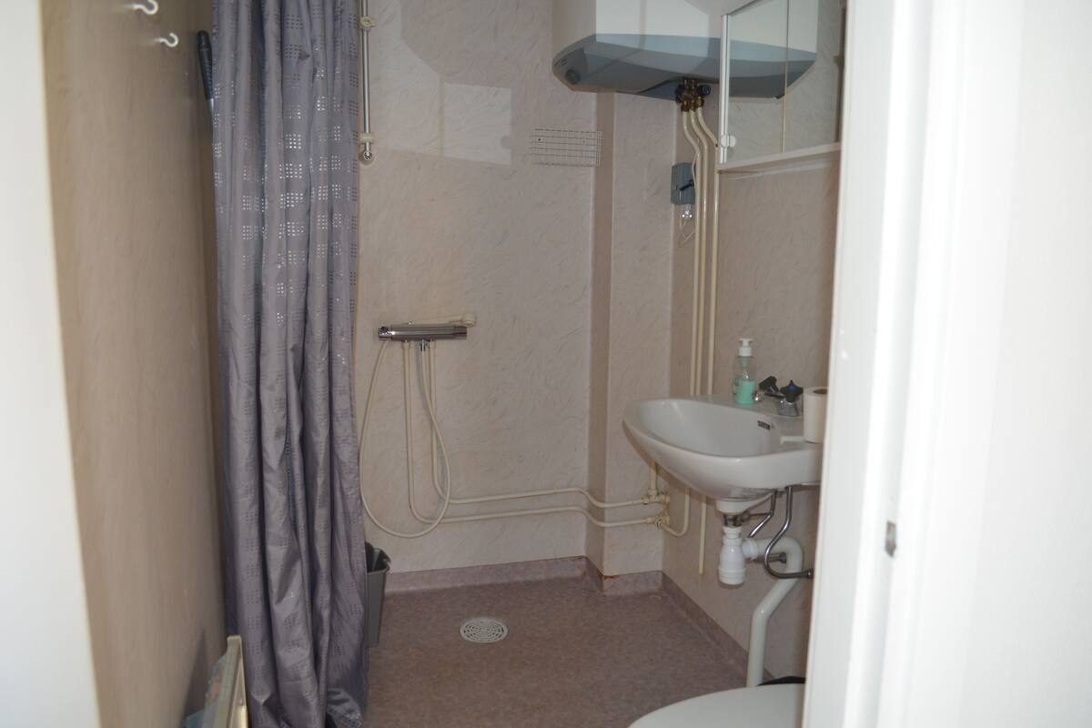Ein kleines Badezimmer mit Dusche, Waschbecken und Toilette.
