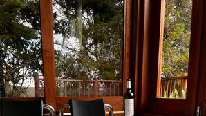 A person relaxing in a hot tub with a glass of red wine, surrounded by wooden furniture and a view of trees. - Quimera Ecolodge Cabana - 7 min JMC Airport (Antioquia)