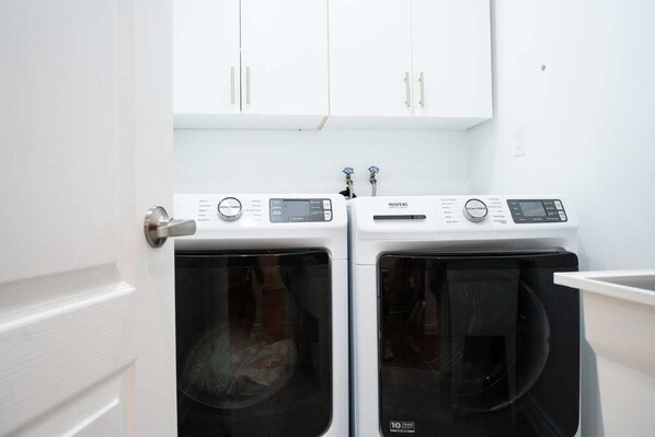 A laundry area with two front-loading washing machines and a white cabinet above them.