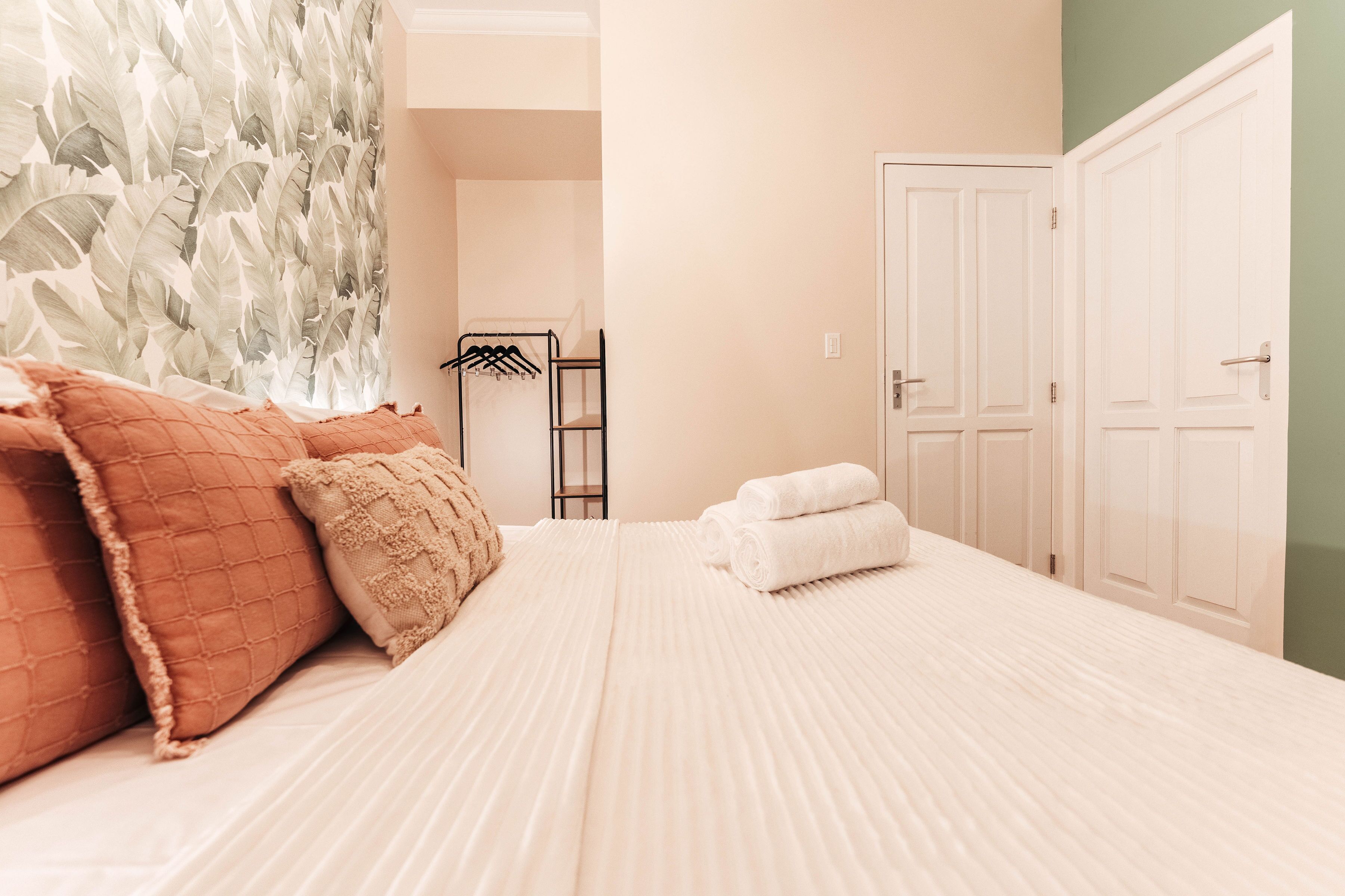 Une chambre à coucher avec un lit, des oreillers, une serviette, une armoire et un miroir.