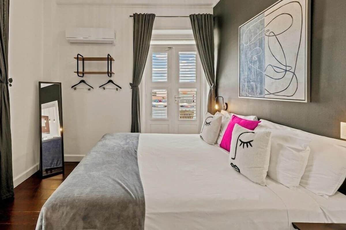 Ein Schlafzimmer mit Bett, Spiegel, Kleiderschrank und einer Tür mit Vorhängen.