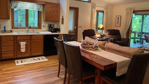 Een gezellige keuken met houten kastjes, een eethoek met een tafel en stoelen, en een plafondventilator.
