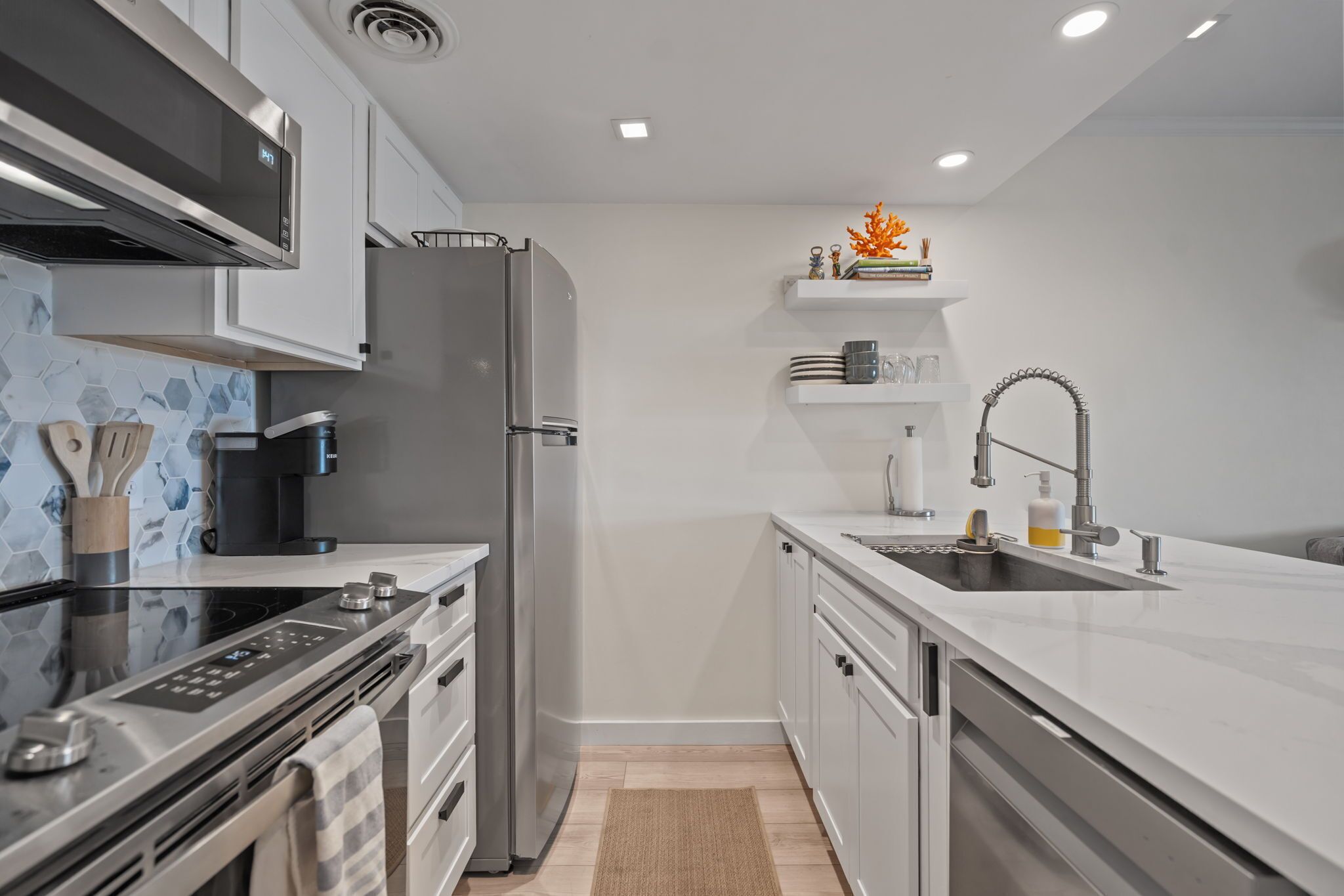 A modern kitchen with a stainless steel refrigerator, built-in oven, and a coffee machine.