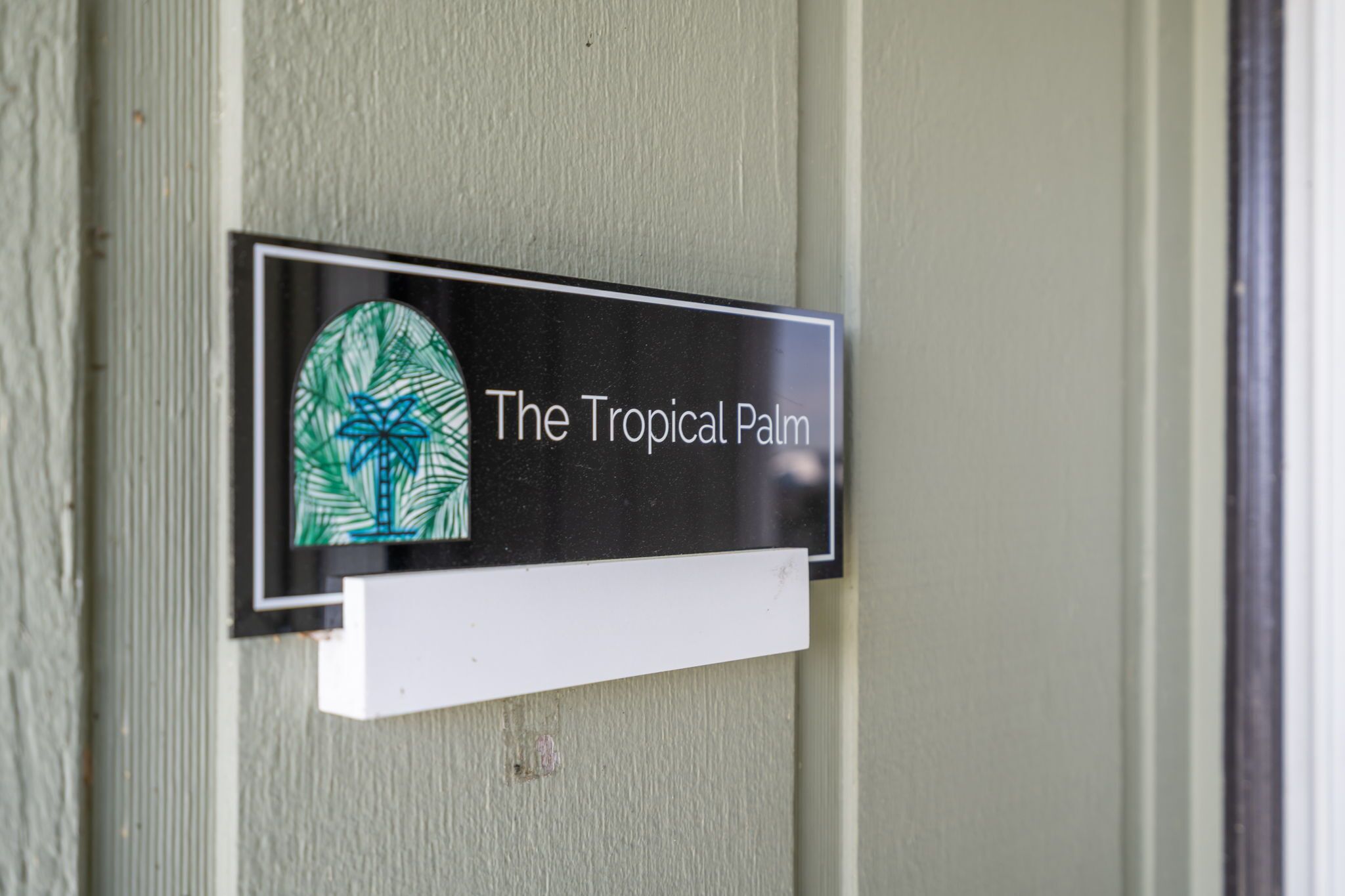 A sign with the text 'The Tropical Palm' on a building's exterior.