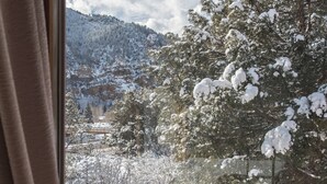 A snowy mountain landscape visible through a window with a wooden railing.