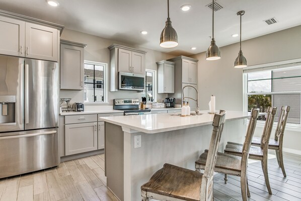 A modern kitchen with stainless steel appliances, a central island, and pendant lighting.