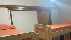 Une chambre avec un lit superposé, dont la structure est en bois et la literie est orange.