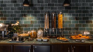 A buffet setup with various food items, including pastries and condiments, against a tiled wall. - Hotel Korona (Sighisoara)