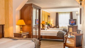 A hotel room with two beds, wooden furniture, a television, and lamps. - Hotel Korona (Sighisoara)