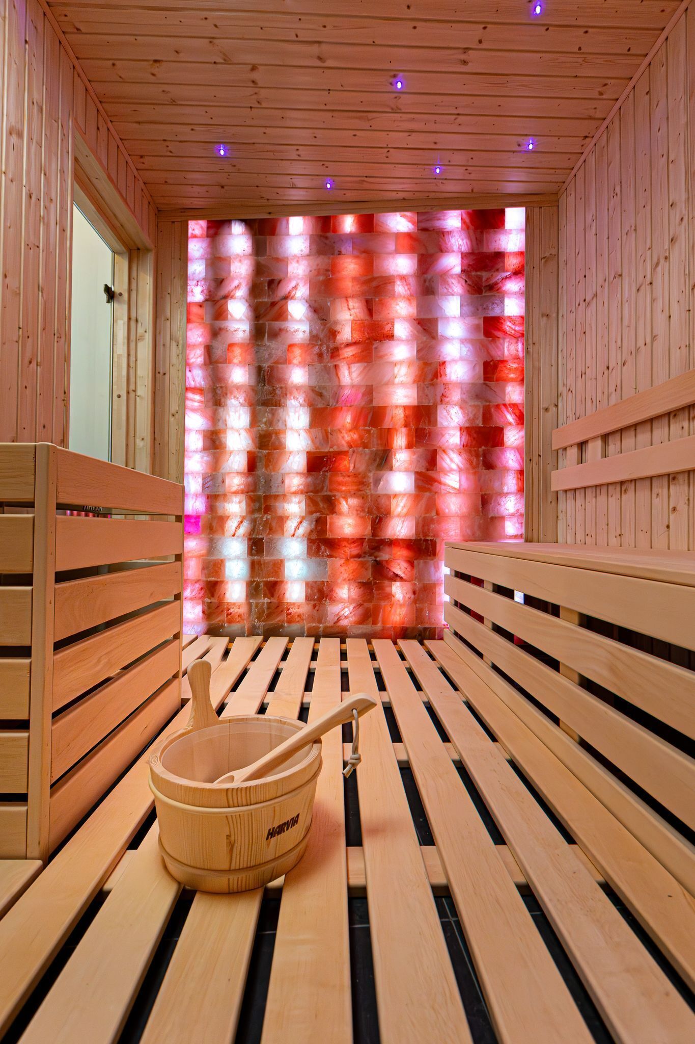 A wooden sauna room with benches and a wooden bucket with a ladle.