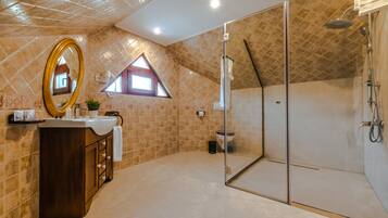 Un baño con ducha de vidrio, tocador con espejo y una ventana pequeña.