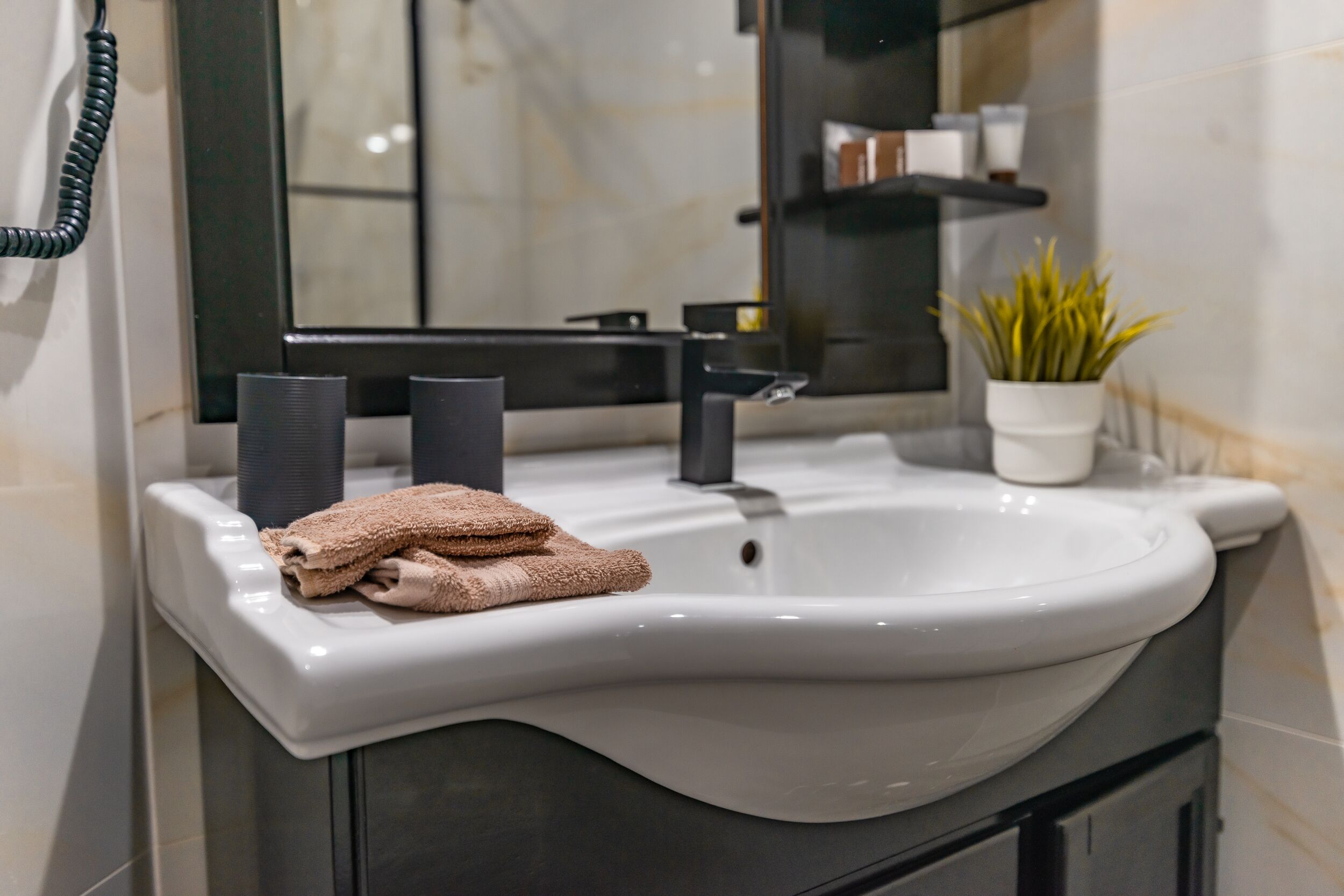 Une salle de bain moderne avec un lavabo blanc, un robinet noir et un porte-serviettes.