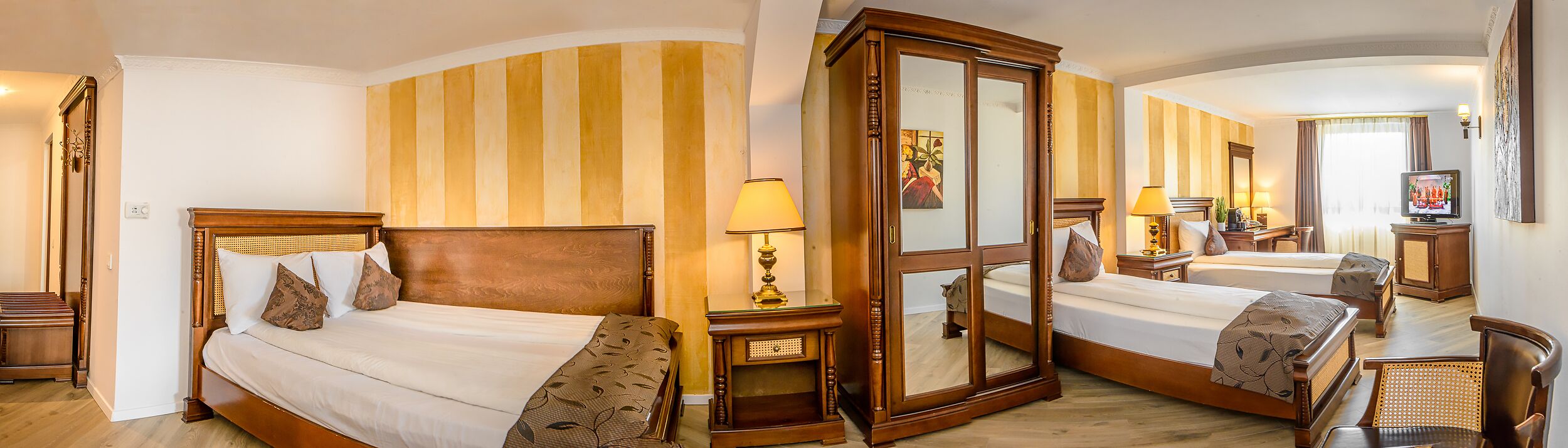 A hotel room with two beds, a large mirror, and a television.