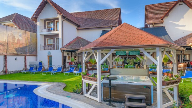 A pool area with lounge chairs, a hot tub, and a gazebo. - Hotel Korona (Sighisoara)