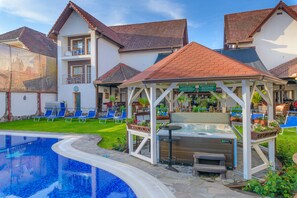 A pool area with lounge chairs, a hot tub, and a gazebo. - Hotel Korona (Sighisoara)