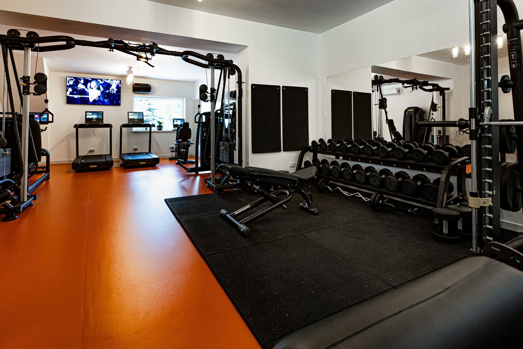 A gym with exercise equipment, treadmills, and dumbbells.