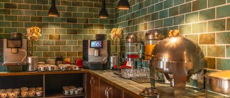 A kitchen with green tiled walls, wooden cabinets, and stainless steel appliances.