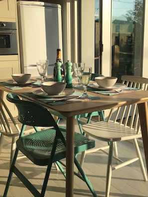 Un espace de restauration en plein air avec une table dressée pour deux personnes, entourée de chaises vertes.