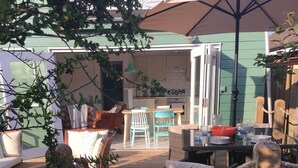 Un espace extérieur aménagé en terrasse, avec une table et des chaises, une table à manger et un grand parasol.