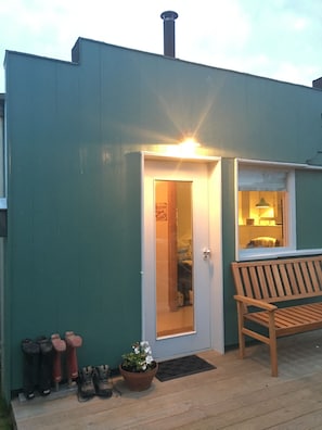 Un bâtiment avec une porte, un banc et un pot de fleurs.