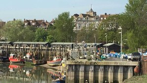 Un quai au bord de l’eau avec des bateaux, une jetée et un bâtiment en arrière-plan.