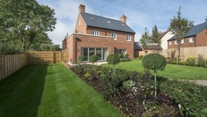 A two-story brick house with a well-maintained lawn and garden.