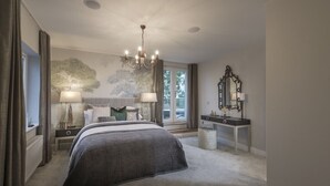 A bedroom with a large bed, two bedside tables with lamps, a dresser, a mirror, and a window with curtains.